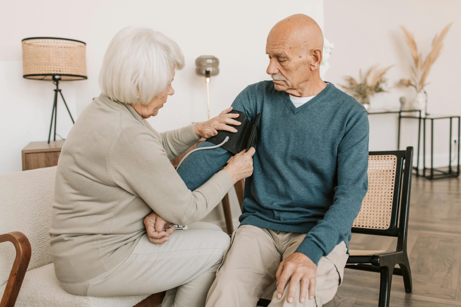 A woman checking an older man's blood pressure at home