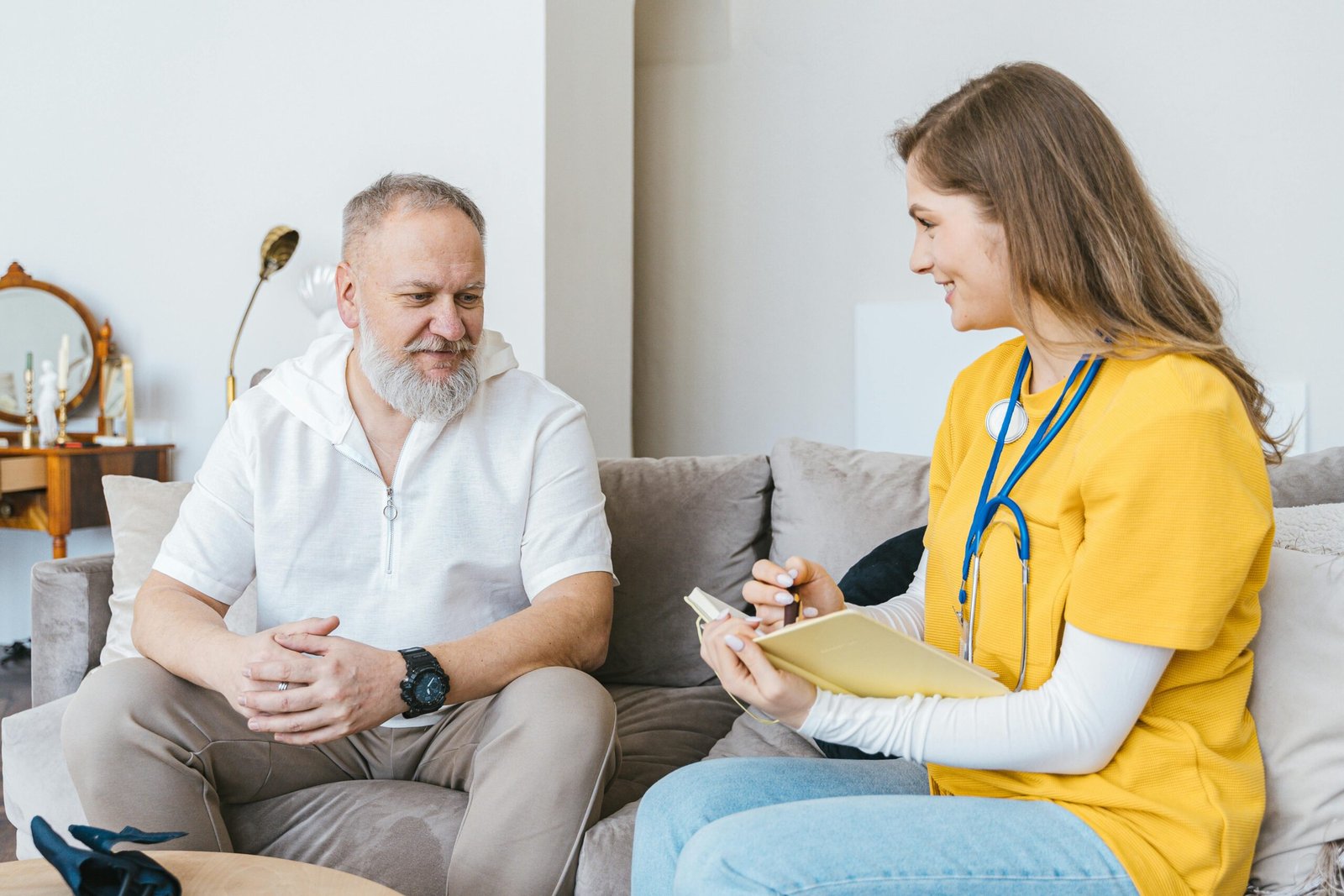 A healthcare professional smiling while talking with an older man at home